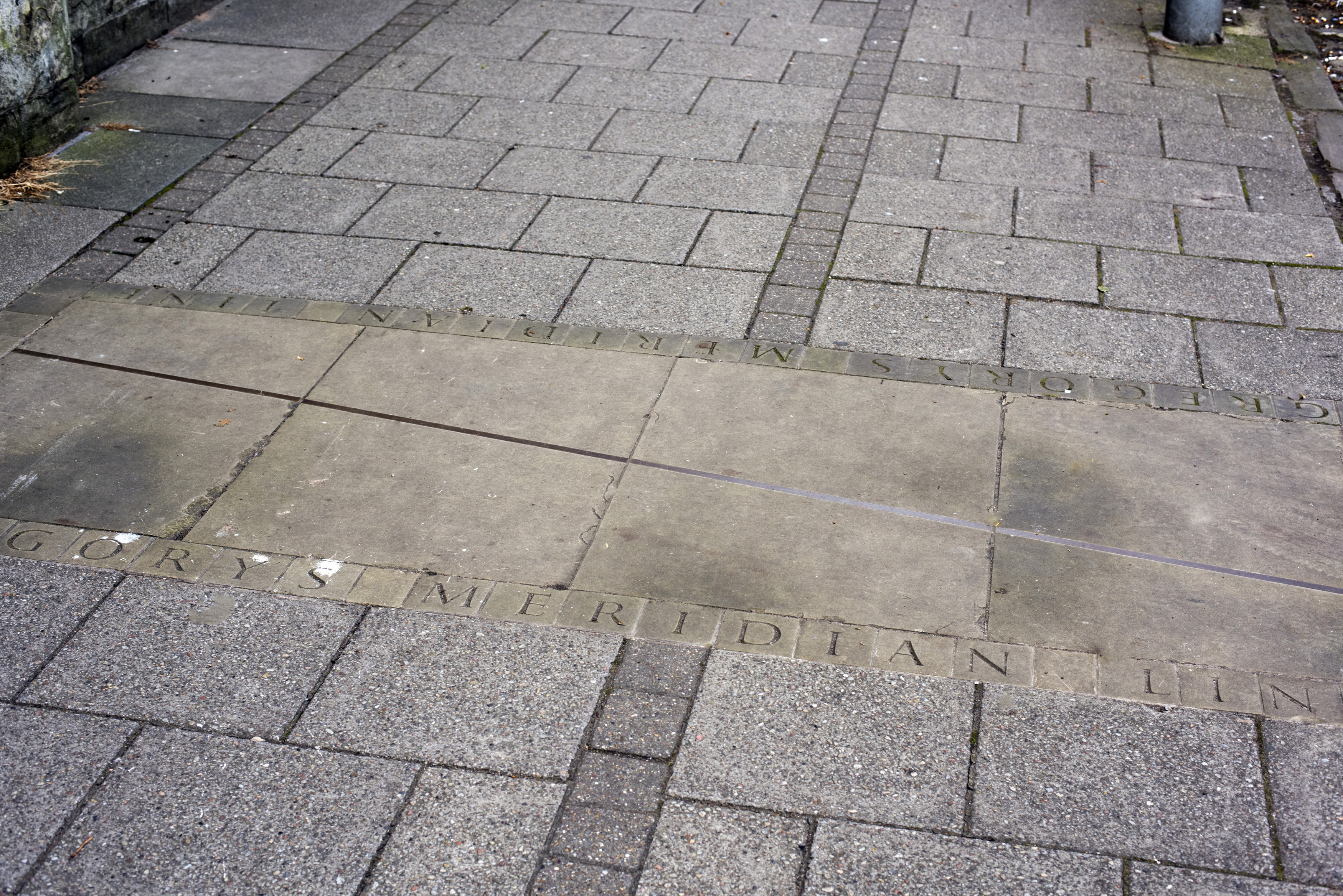 an image of First person high angle view on carved line and letters in sidewalk at the famous Gregorys Meridian in Scotland